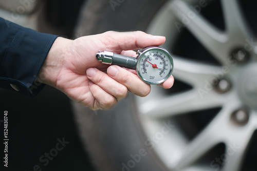Hand holding pressure gauge for car tyre pressure measurement