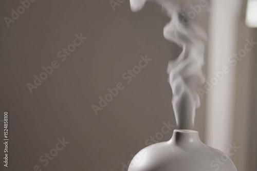 Relaxing ambient clip of essential oil diffuser releasing steam in minimalist room. Generative AI