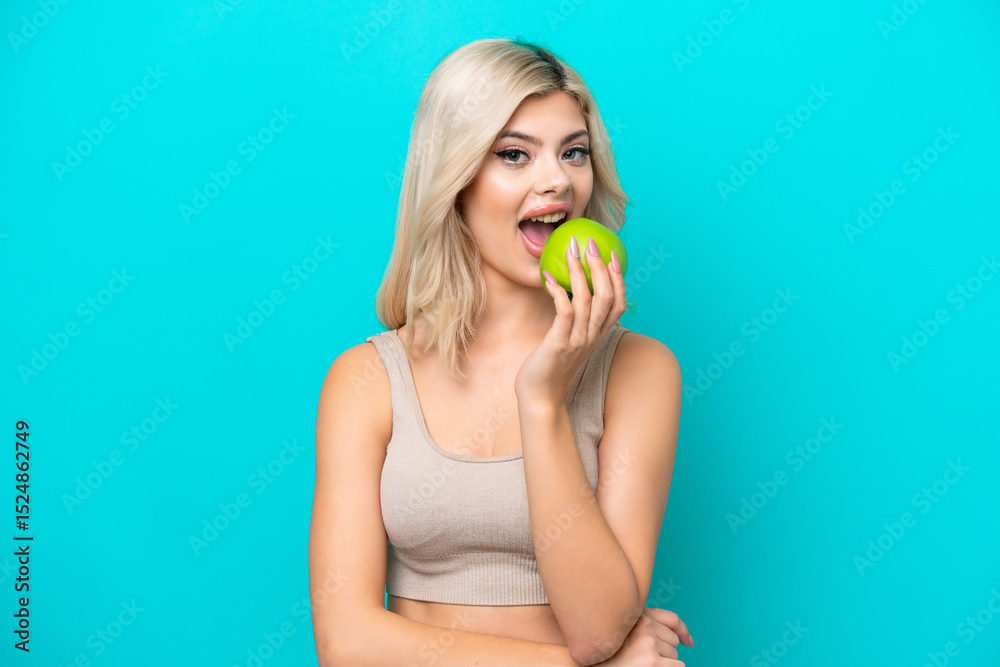Young Russian woman isolated on blue background eating an apple Young Russian woman isolated on blue background eating an apple