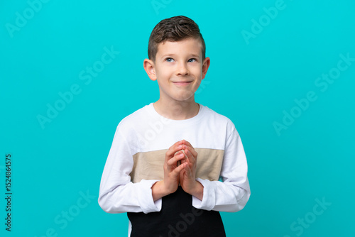 Little kid boy isolated on blue background scheming something