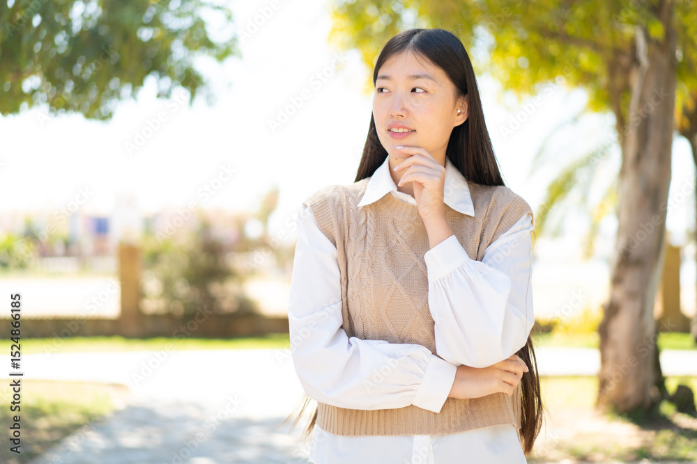 Pretty Chinese woman at outdoors looking to the side Pretty Chinese woman at outdoors looking to the side