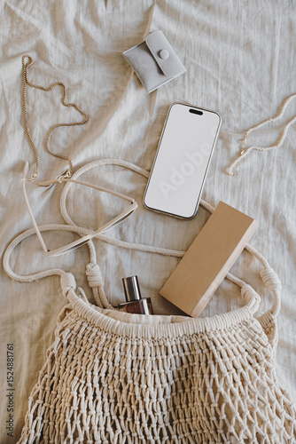 Smartphone and Accessories in Natural Mesh Bag on Neutral Fabric Background