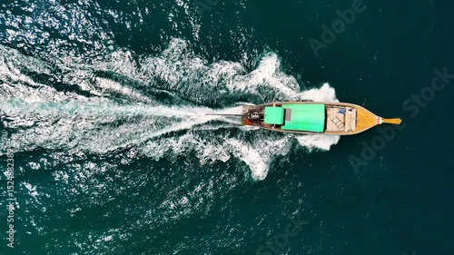 Traditional thai long tail boat sailing through vibrant turquoise waters, aerial view. Phi phi, Phuket, Thailand.