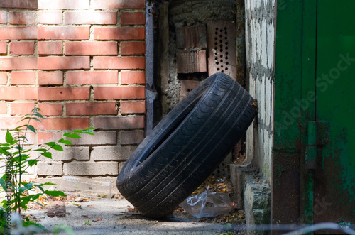 A tire is laying on the ground next to a brick wall. The tire is upside down and he is discarded. The scene gives off a sense of neglect and abandonment photo