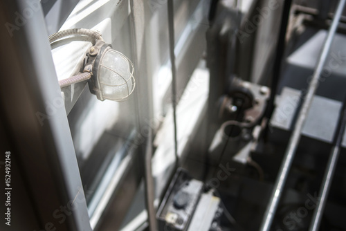 Protected light fixture with metal mesh casing in an elevator shaft, showcasing industrial safety design