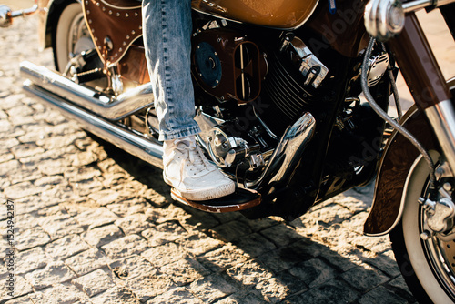 Quadro em tela Motorcyclist resting foot on footrest of vintage motorcycle on cobblestone stree