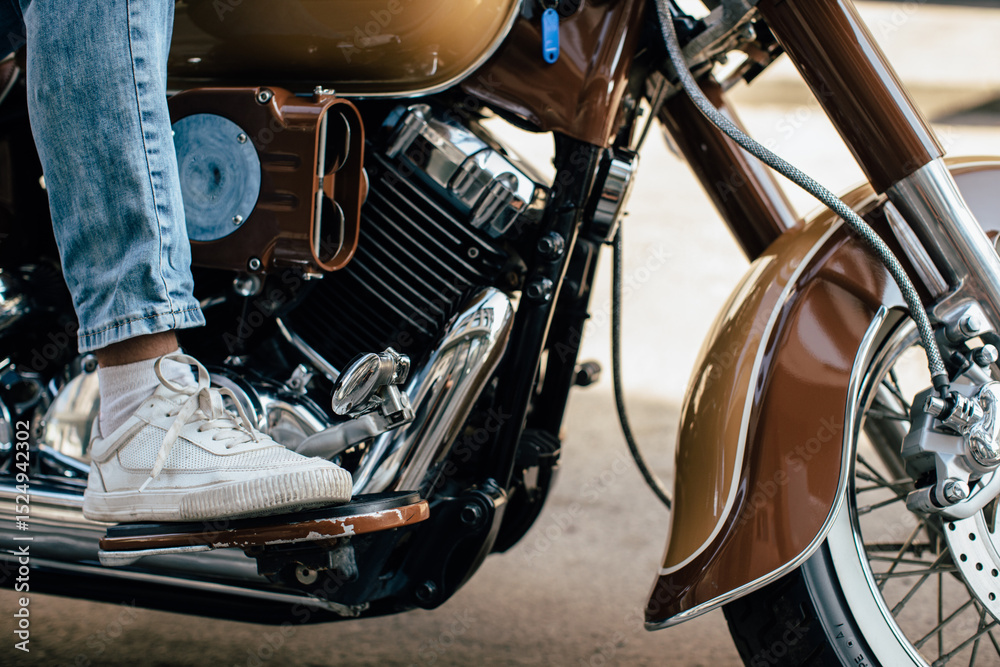 Obraz premium Motorcyclist placing foot on footrest of brown motorcycle