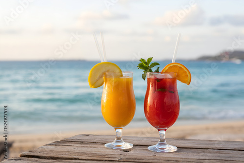 Tropical cocktails with garnishes on weathered wood against blurred ocean