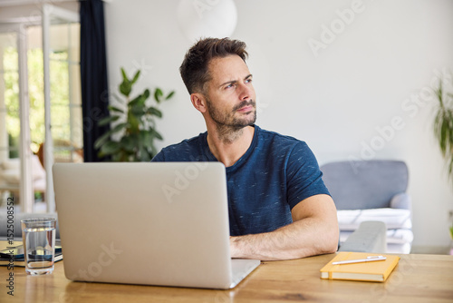 Thoughtful man working from home with laptop
