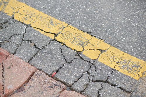 Foto Cracked pavement with faded yellow line on city street