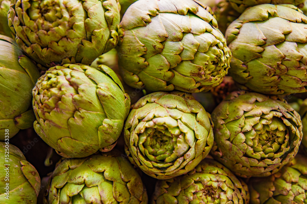 Fototapeta premium Fresh artichokes at the Central Market of Valencia, Spain, displayed in a vibrant rustic background. Perfect high-quality image for travel, gastronomy, and cultural projects. Showcasing Mediterranean 