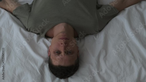 Man lying in bed alone, looking at ceiling closeup. Male suffering from depression. Top view
