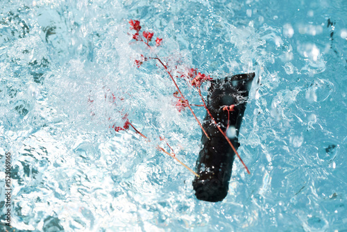 Flowers fall into water, creating ripples and splashes in a refreshing pool during a sunny day