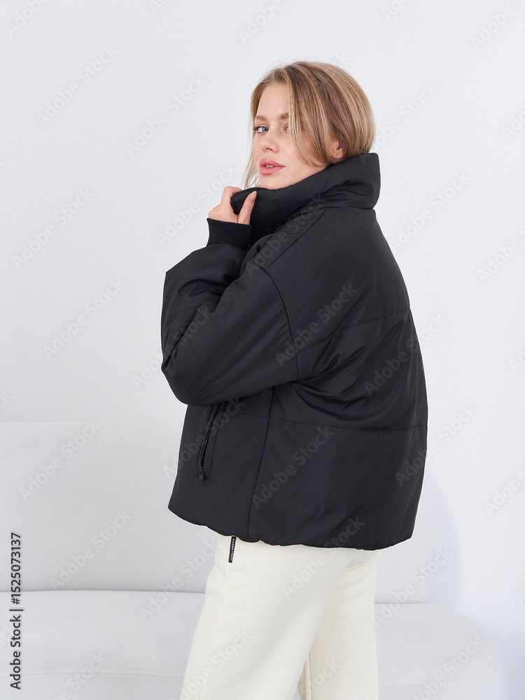 Fashion model showcasing stylish black outerwear in modern studio setting Fashion model showcasing stylish black outerwear in modern studio setting