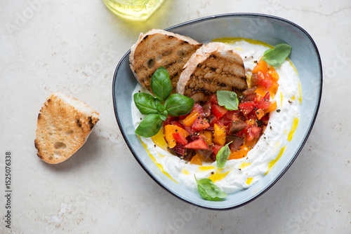 Ricotta dipping sauce with chopped tomatoes on a light-beige stone background, horizontal shot, high angle view