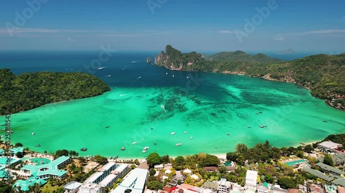 Aerial view of Maya bay, turquoise waters, traditional longtails boats floating near Phi phi island shoreline, Thailand.