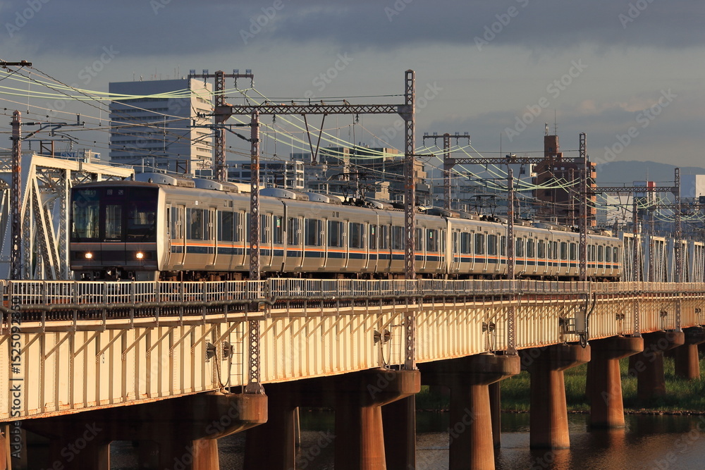 Naklejka premium 朝日に照らされながら淀川を渡るJR西日本321系電車_2010/8/26撮影