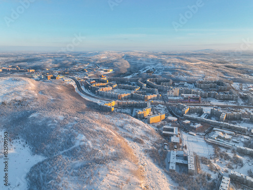 Aerial view of a residential area in Murmansk, with snow-covered buildings and trees under a clear winter sky, Russia