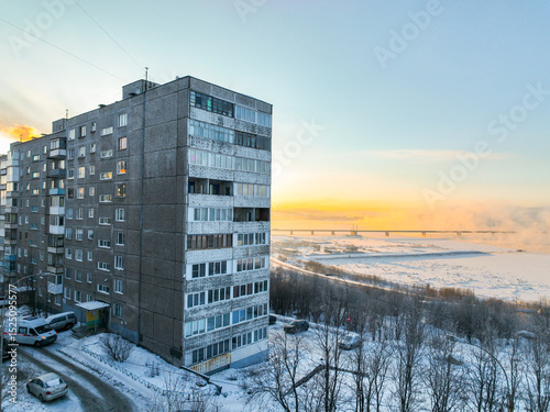 Aerial view of a multi-story apartment building overlooking a frozen river and bridge in Murmansk, Russia