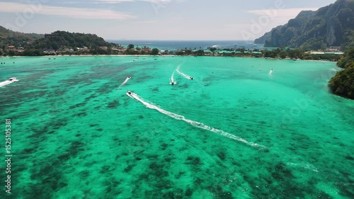 Aerial view of Maya bay, turquoise waters, traditional longtails boats floating near Phi phi island shoreline, Thailand.