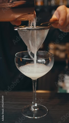 close-up view cocktail in restaurant. barman behind counter makes cocktails with ice. ice cubes in margarita glass. bartender shakes shaker. special serving alcoholic cocktail. drops fall into glass