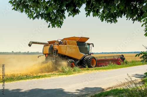 Yellow combine harvester at the edge of a field during harvesting