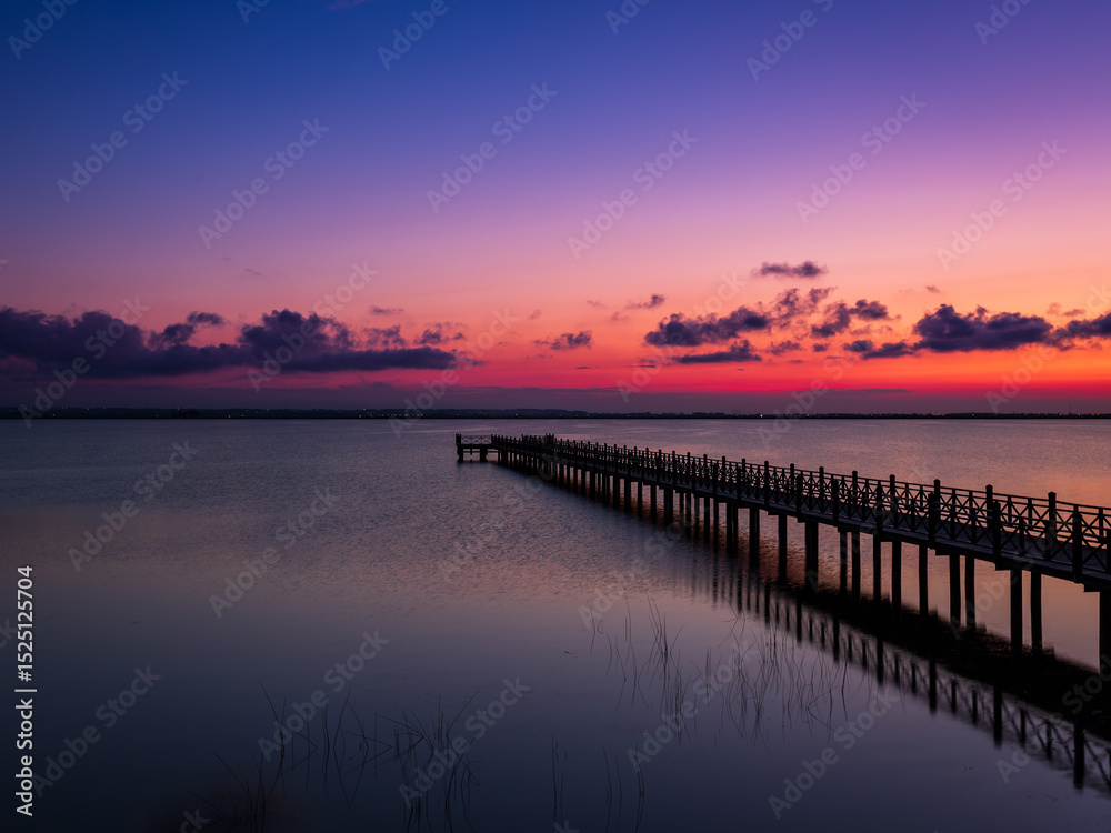 Obraz premium Sunset over the pier and calm sea, peaceful landscape at dusk 