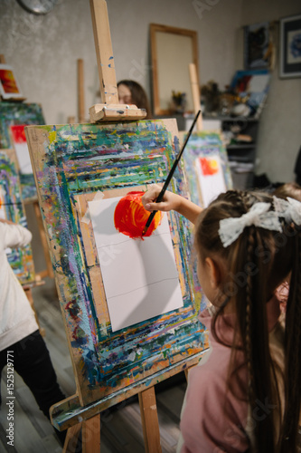 Girl enjoys painting in workshop. Art lesson. Education and learning concept. Child draw a picture in art class. School kid drawing with brush landscapes on easel. Mix and combine colors.
