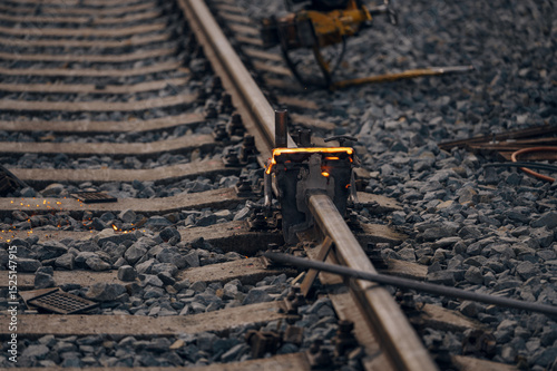 A worker in the process of a railroad track weld repair, reconstruction with a freight train passing