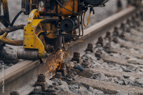 A worker in the process of a railroad track weld repair, reconstruction with a freight train passing