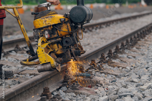 A worker in the process of a railroad track weld repair, reconstruction with a freight train passing