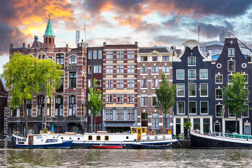 Obraz premium The unique architecture of Amsterdam at twilight, showing the old city merchant buildings and boats along the canal.