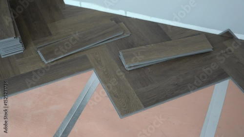 An unrecognizable person shows the process of laying flooring during renovation in an apartment or house. Laminate or quartz vinyl coating in dark color with a wood pattern. High quality 4k footage
