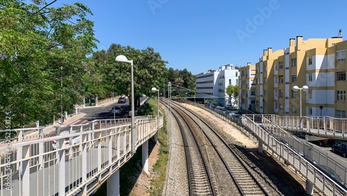 Sunlit urban railway curves amidst pastel facades, echoing Euro commutes and secretive tracks on World Urbanism Day