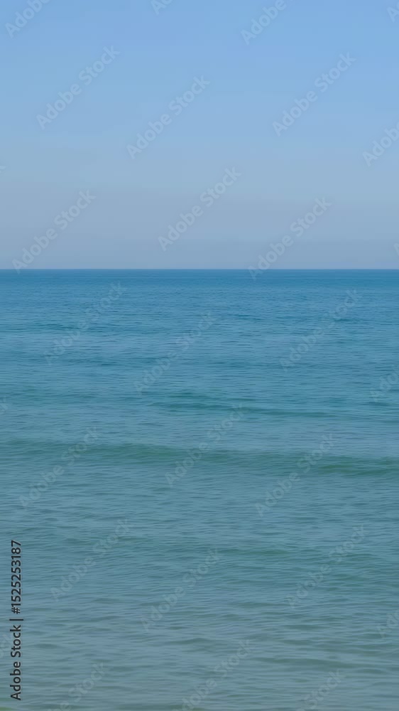 Tranquil ocean waves gently lapping under clear blue skies at horizon Tranquil ocean waves gently lapping under clear blue skies at horizon
