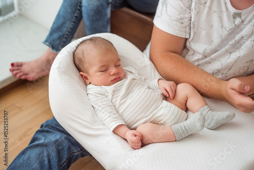 Newborn baby sleeping peacefully on father's lap, enjoying the warmth and comfort of his presence, creating a heartwarming scene of family bonding and paternal love