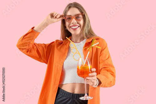 Young woman in sunglasses with aperol spritz cocktail on pink background