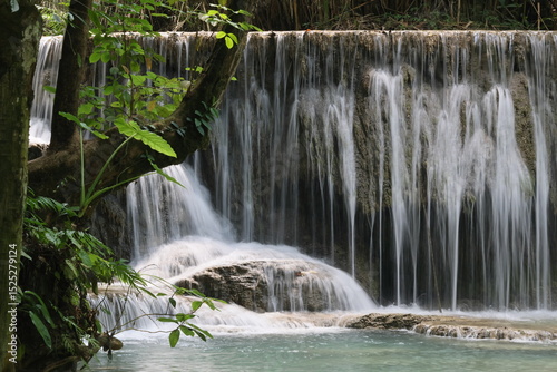 Experience the natural beauty of a flowing waterfall cascading over rocks in a lush green forest park, Kouangsi waterfall Luang Prabang