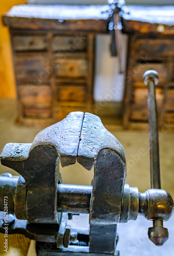 Wallpaper Mural Vintage woodworking vise showcased in a rustic workshop setting with tools and cabinets arranged behind it Torontodigital.ca