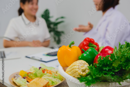 An Asian female nutritionist attentively discusses dietary habits with a patient, offering personalized nutrition advice. She explains healthy food choices, emphasizes balanced meals