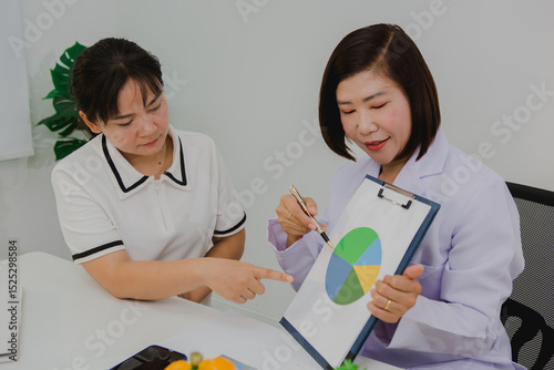 An Asian female nutritionist attentively discusses dietary habits with a patient, offering personalized nutrition advice. She explains healthy food choices, emphasizes balanced meals