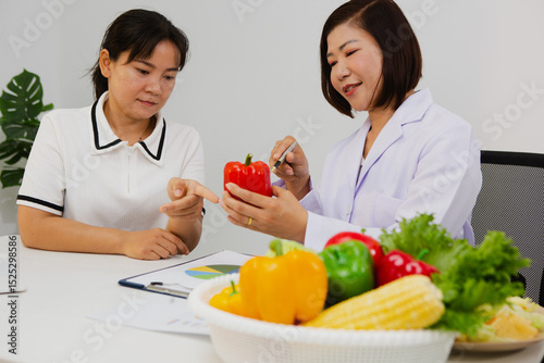 An Asian female nutritionist attentively discusses dietary habits with a patient, offering personalized nutrition advice. She explains healthy food choices, emphasizes balanced meals