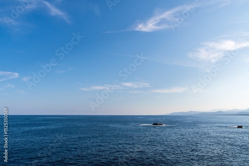 遠くの山並みを望む青い海と大空のパノラマ