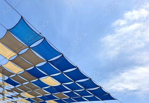 Fotografie Blue and Beige Diamond Shaped Shade Sails Against Sky