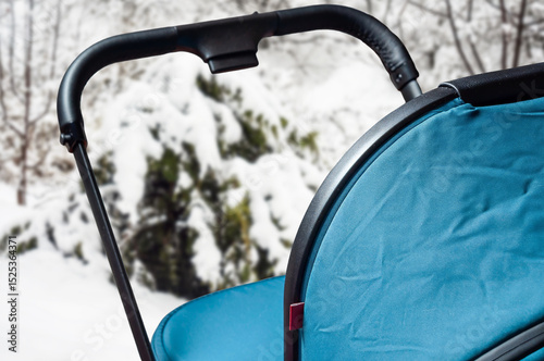 A close-up view of a baby stroller, perfectly designed for winter outings with a snowy backdrop.