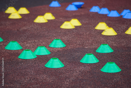 Brightly colored plastic training cones arranged on a textured sports surface, used for agility drills or athletic practice setups.