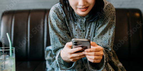 ソファに座ってスマートフォンを使う若い女性