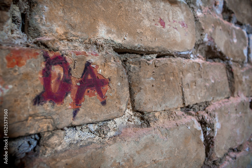 Angled perspective view of an old brick wall, graffiti letters DA
