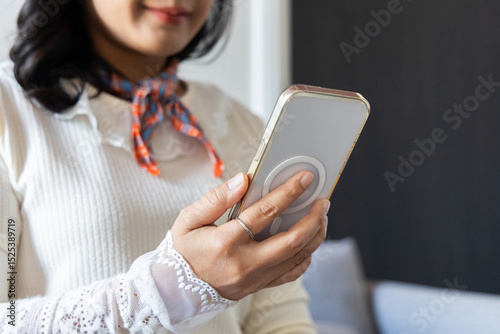 Closeup hands of happy smiling young woman using smartphone to social media online at home. Young woman looking at cellphone holding mobile cell phone chat message
