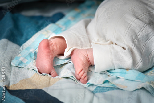 Newborn baby's wrinkled and cracked feet resting on a bed, showcasing delicate infant skin details